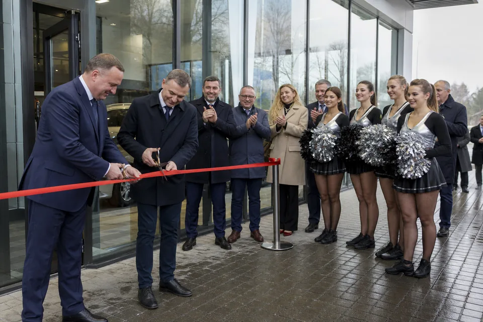 Przecięcie wstęgi przed nowym salonem samochodowym, obok grupa taneczna gotowa do wejścia